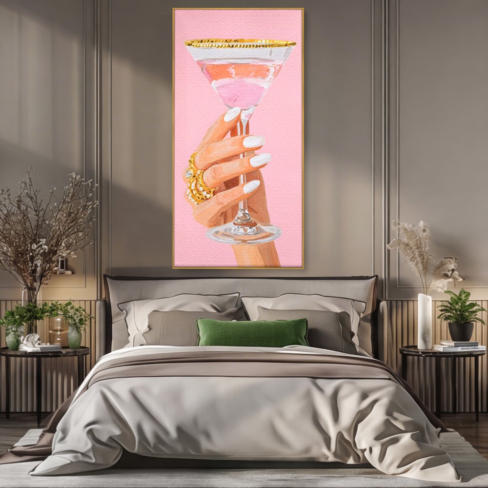 Tablou canvas cu ilustratie cu mana care tine pahar de cocktail, in rama de aluminiu auriu, pe perete intr-un dormitor